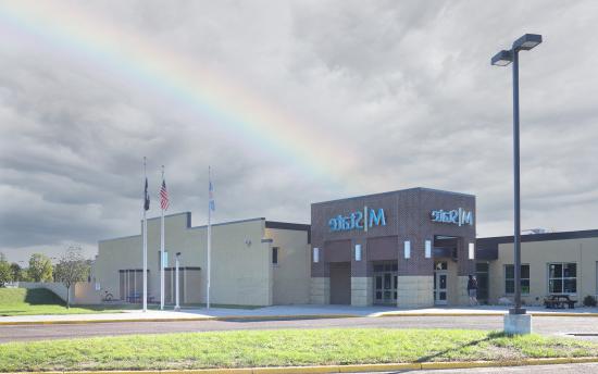 A photo of the exterior of M州-Wadena with a rainbow occurring over the building 